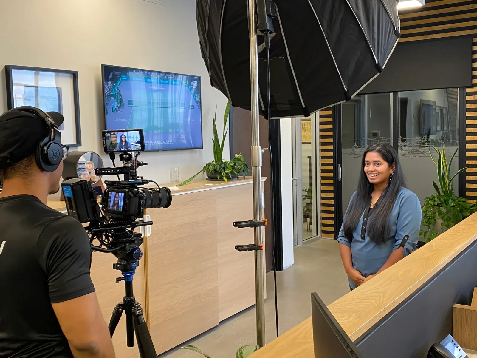 Professional brand video shoot with subject being filmed in a modern office setting